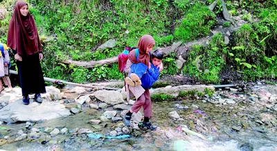 school children face risks in crossing stream in bandipora in absence of bridge